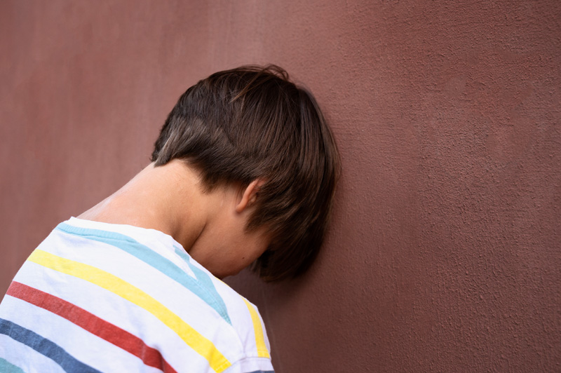 ребенок с аутоагрессией стоит лицом к стене